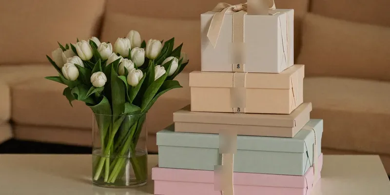 Stack of pastel wrapped gifts with white tulips