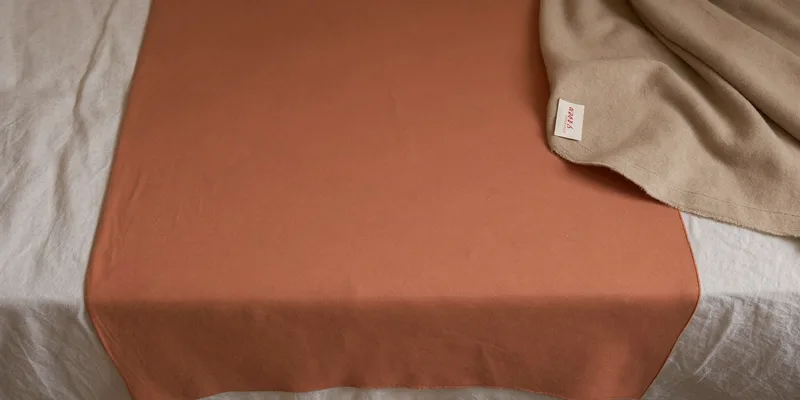 Generously cut soft rose fabric band on a bed