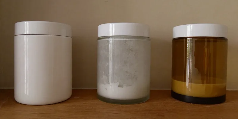 Three plain cream jars compared on a wooden shelf