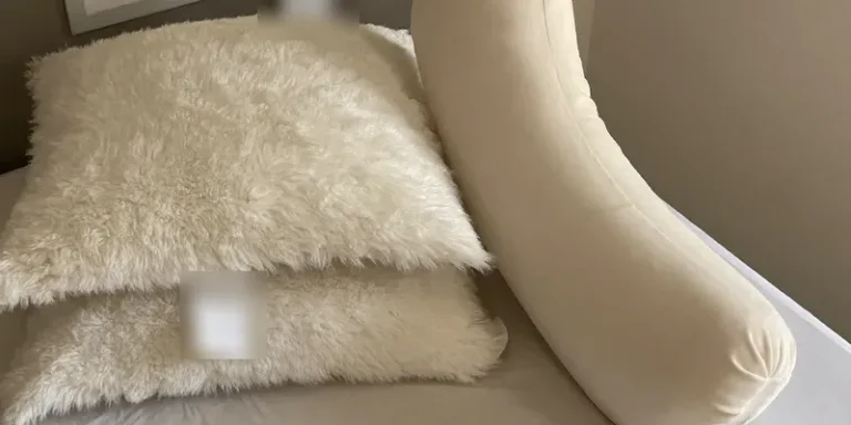 White bed pillows stacked beside a pregnancy pillow