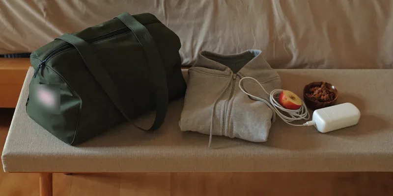 Green duffel bag with hoodie, charger and snacks