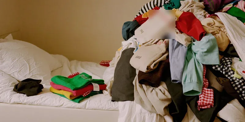 Neat stack of garments beside an overflowing pile