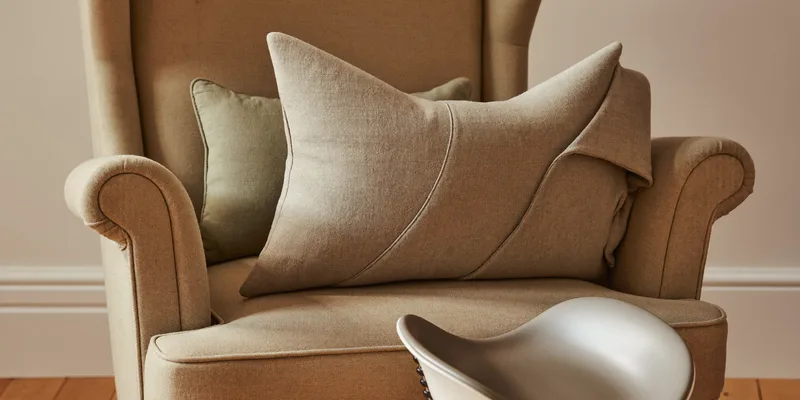 Crescent nursing pillow on an armchair with footstool