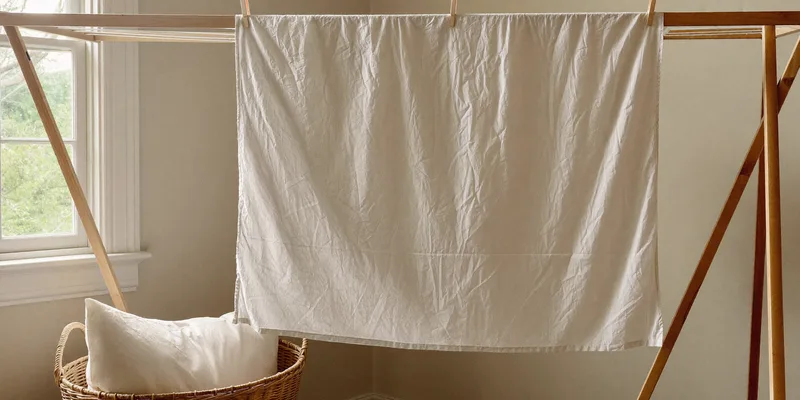 Plain pillow cover drying on a wooden rack