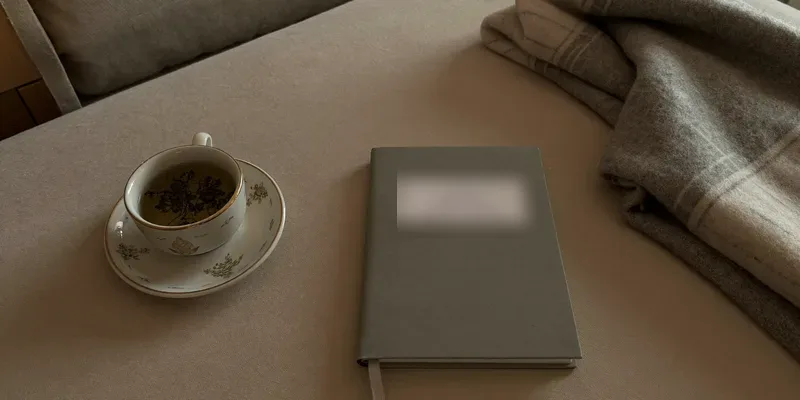 Cup of tea, notebook and blanket on a low table