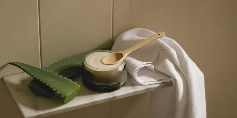 Open jar of cream with aloe leaf and muslin cloth