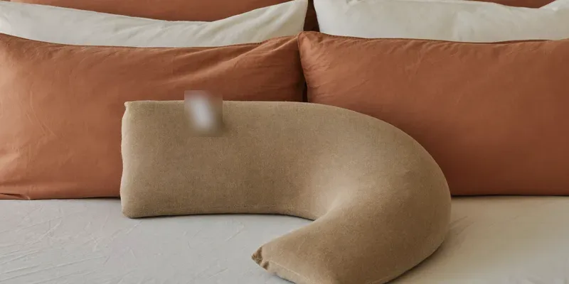 J-shaped pregnancy pillow with hook curve on a bed