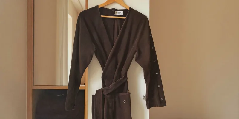 Dark plum wrap gown hanging on a wardrobe door