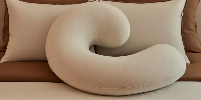 Long curled C-shaped body pillow on layered bedding