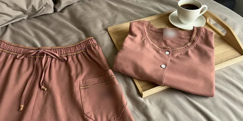 Dusty rose pajama set folded beside a cup of tea