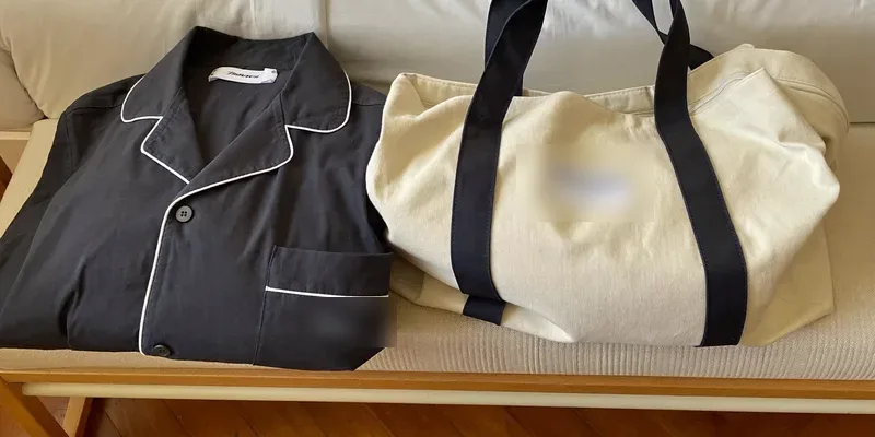 Navy pajama set beside a packed overnight bag