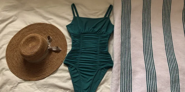 Teal one piece swimsuit with sun hat and towel