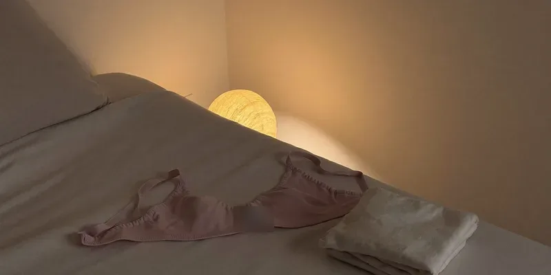 Soft sleep bra draped on a bed by warm lamplight