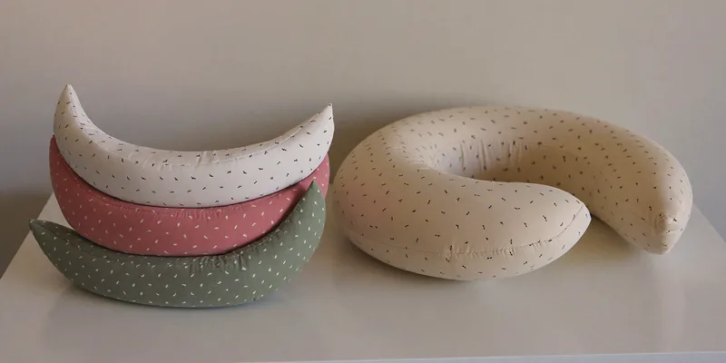 Folded nursing pillow covers beside a bare pillow