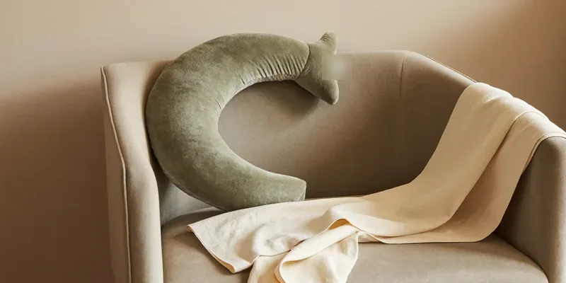 Sage crescent nursing pillow on an armchair