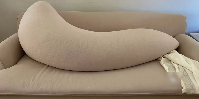 Very wide crescent twin nursing pillow on a sofa