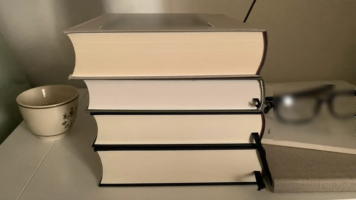Stack of books with a journal on a nightstand