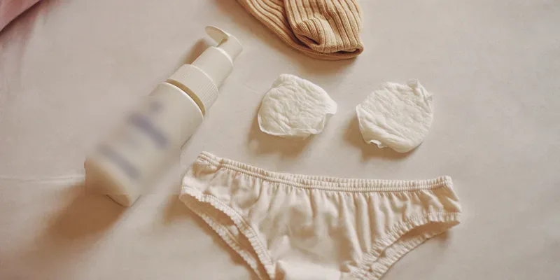 Small set of postpartum essentials on a bed