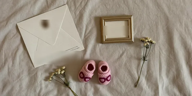 Flat lay with baby shoes, envelope and empty frame