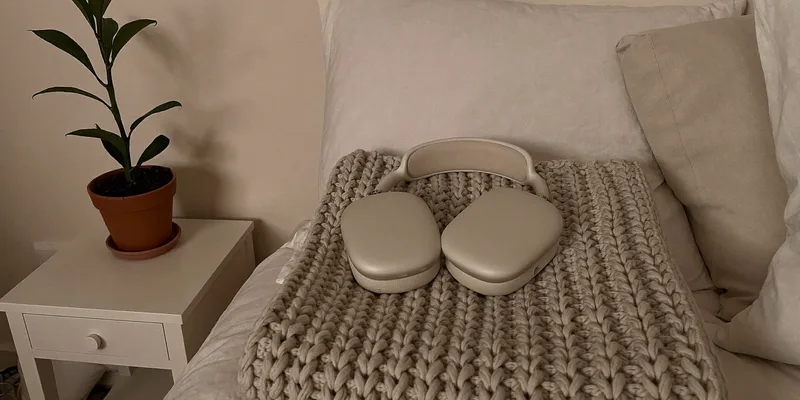 Cream headphones on a folded knit blanket