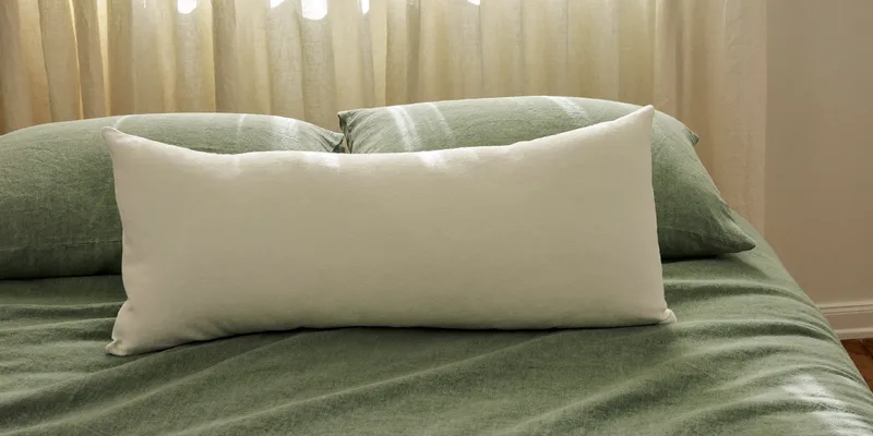Long full body pillow lying diagonally on sage bedding