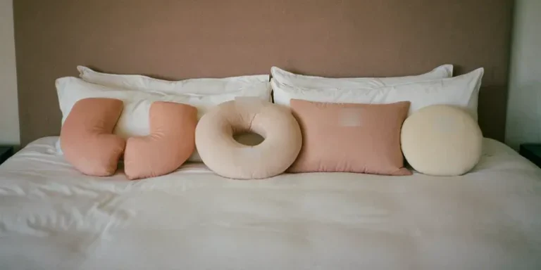 Four different pregnancy pillows lined up on a bed