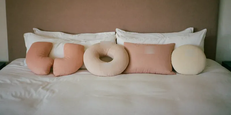 Four different pregnancy pillows lined up on a bed