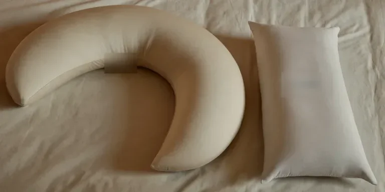 Curved pregnancy pillow beside a straight body pillow