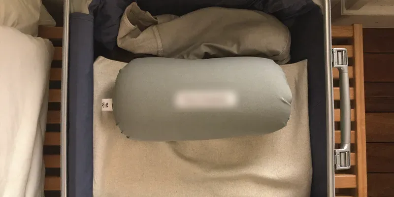 Rolled travel pregnancy pillow inside an open suitcase
