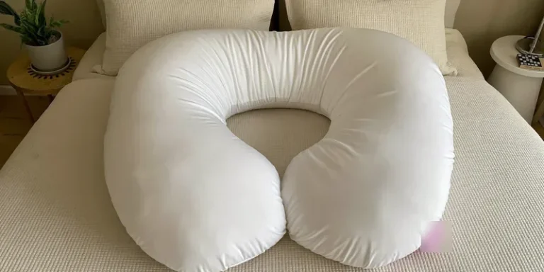 U-shaped pregnancy pillow seen from above on cream bedding