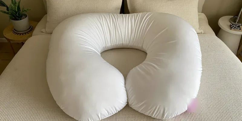 U-shaped pregnancy pillow seen from above on cream bedding