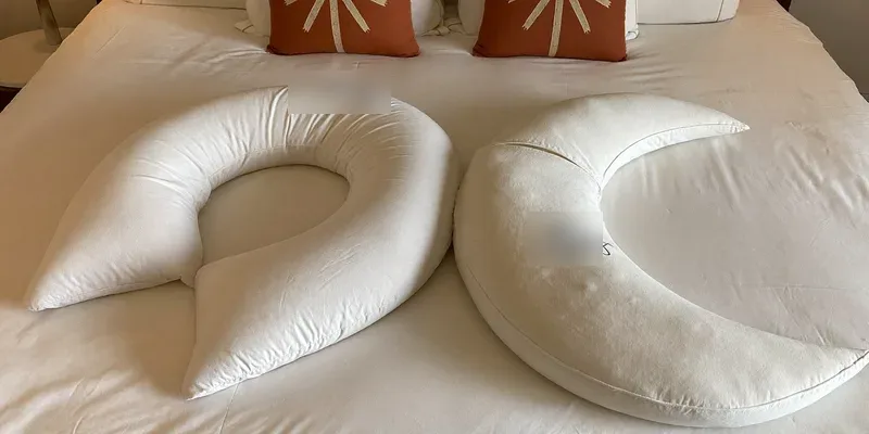U-shaped and C-shaped pregnancy pillows compared on a bed